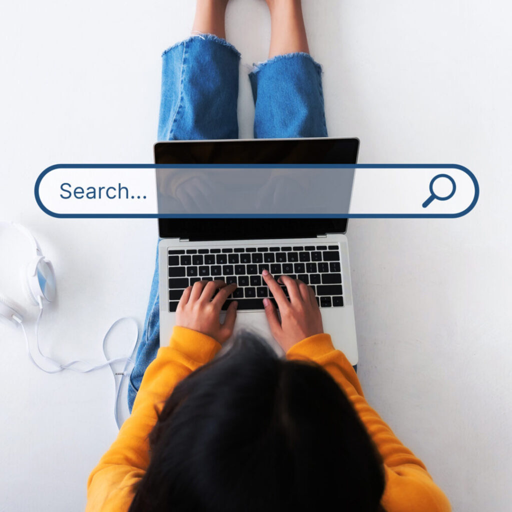 Image of woman from above working on a laptop with a search bar superimposed.